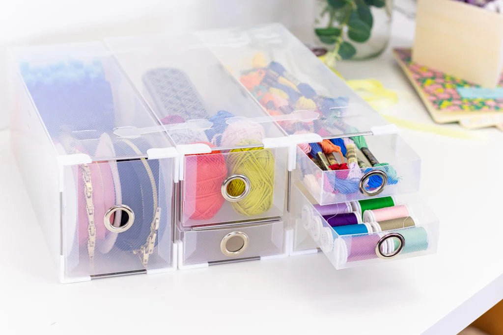 Clear plastic organizer with colorful spools of thread on a white surface