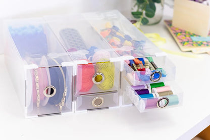 Clear plastic organizer with colorful spools of thread on a white surface