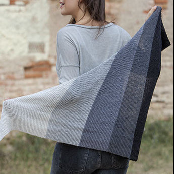 Person holding a striped scarf in front of a brick wall