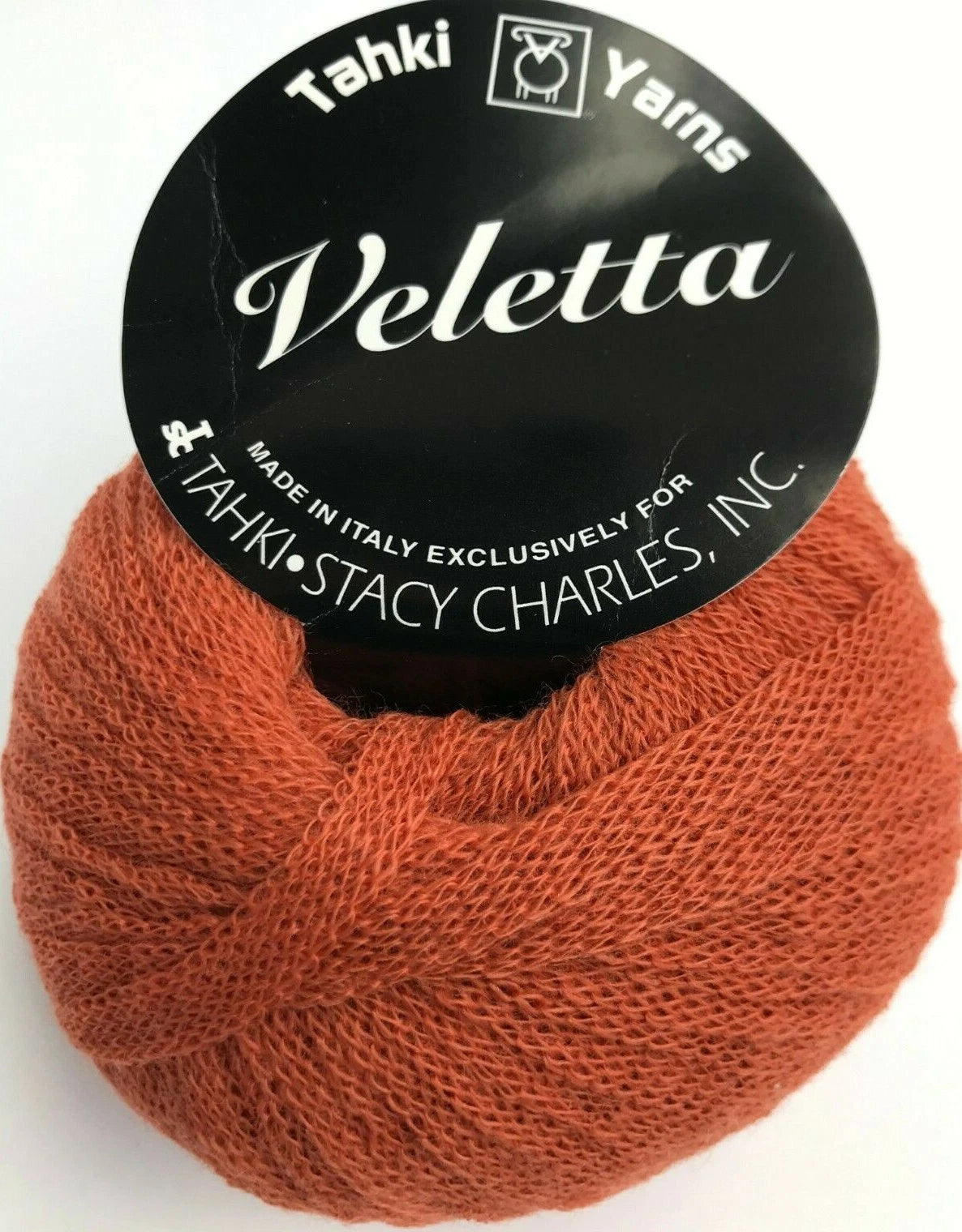 Ball of orange yarn with 'Tahki Yarns Veletta' label on a white background