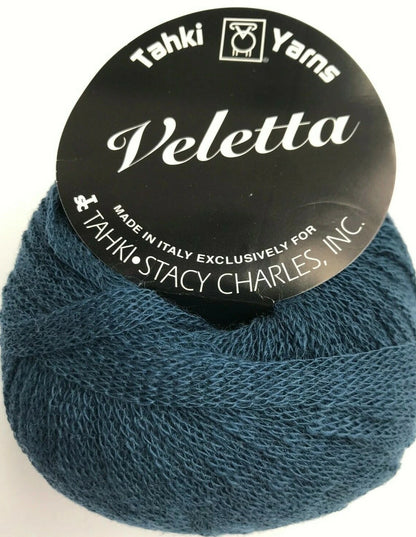 Blue skein of yarn with 'Tahki Yarns Veletta' label on a white background
