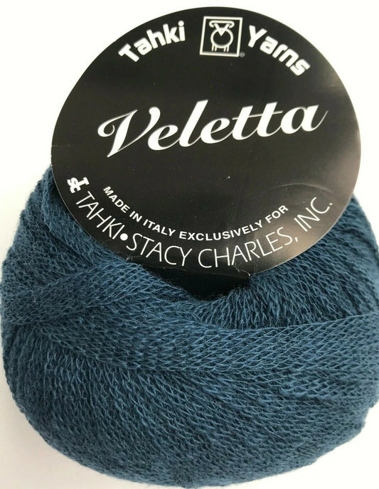 Blue skein of yarn with 'Tahki Yarns Veletta' label on a white background