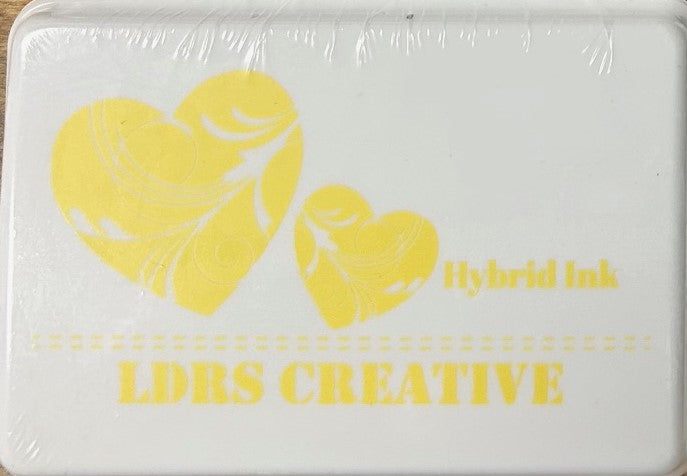 An image of a white ink pad featuring two yellow hearts with white decorative swirls and the text "LDRS CREATIVE Hybrid Ink" in yellow.