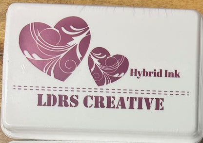An image of a white ink pad featuring two purple hearts and the text "LDRS CREATIVE Hybrid Ink" in a bright purple color.