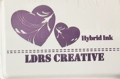 An image of a white ink pad featuring two purple colored hearts with white decorative swirls and the text "LDRS CREATIVE Hybrid Ink" in purple.
