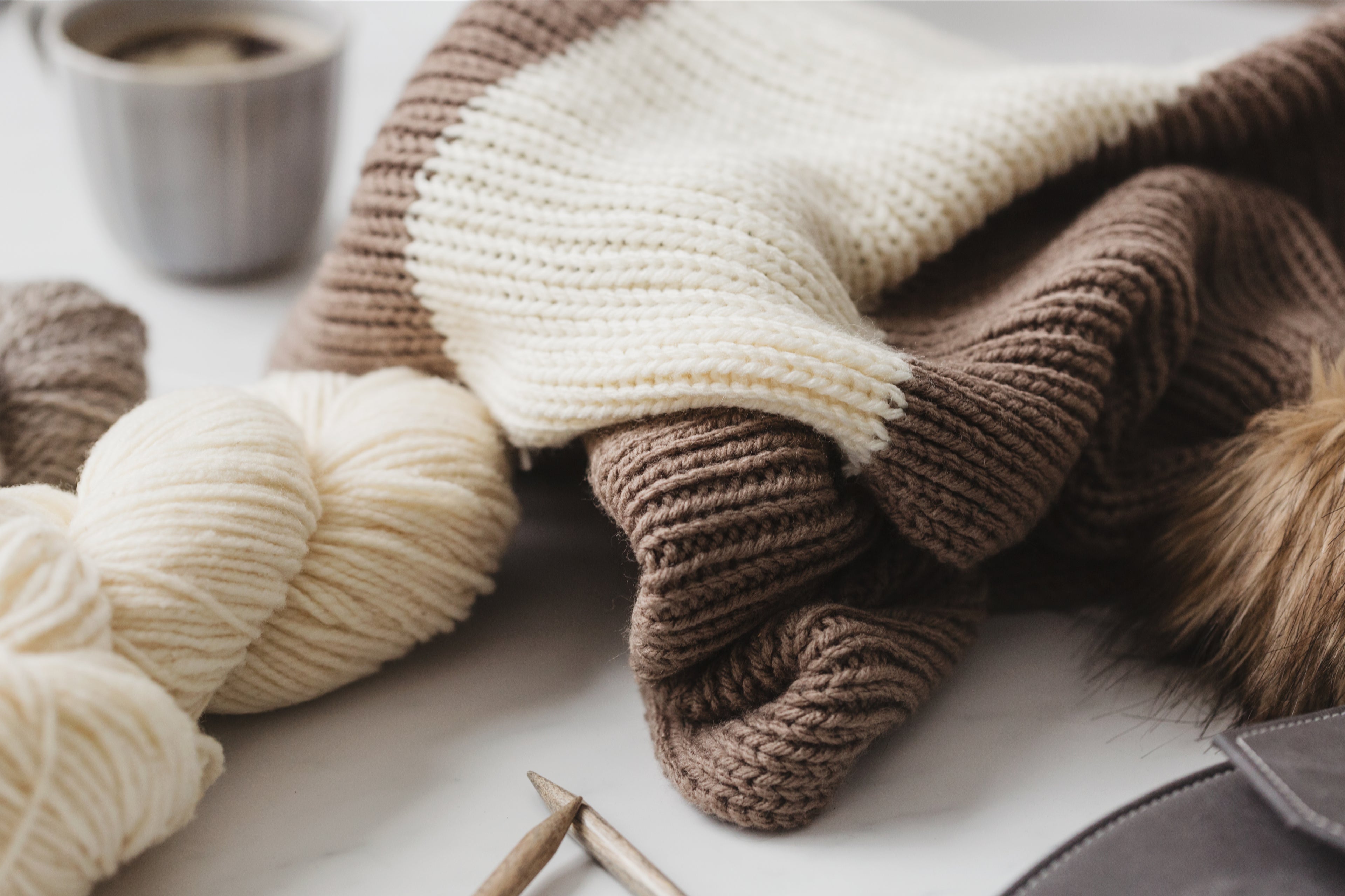 Close-up of brown and cream colored yarn next to a white mug of coffee