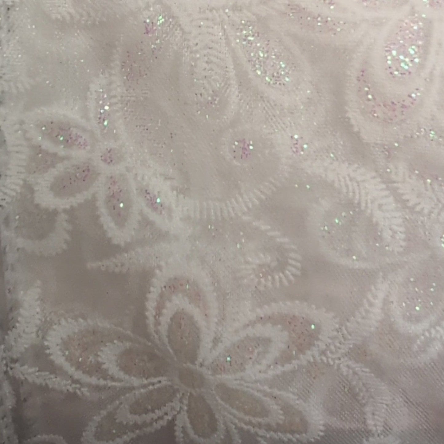 Close-up of a textured fabric with floral patterns and sequins.