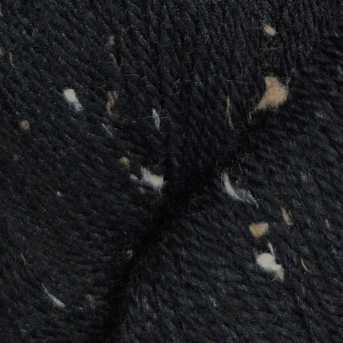 Close-up of dark fabric with small white and beige fibers