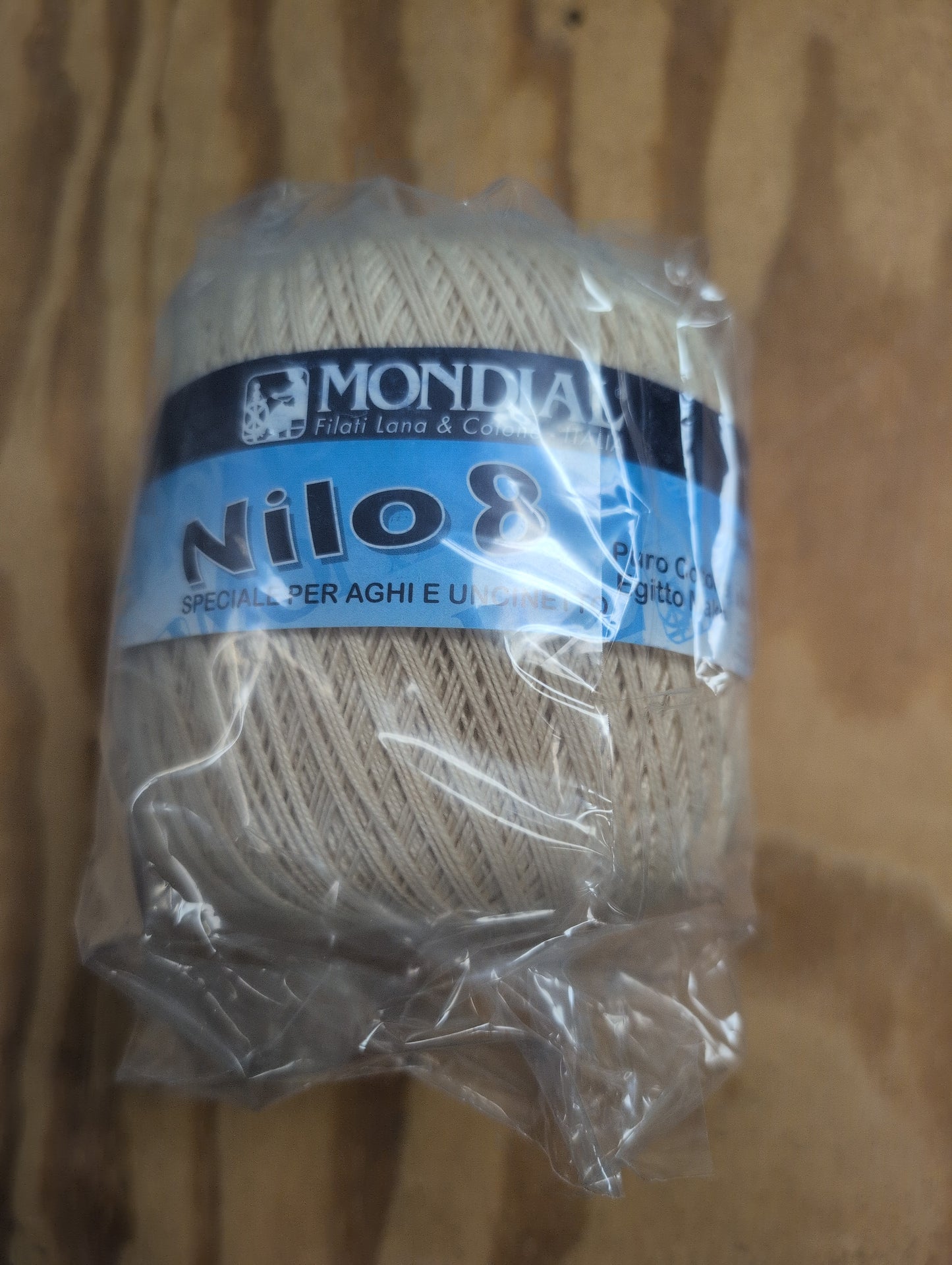 Ball of yarn with a Mondial Nilos label on a wooden surface
