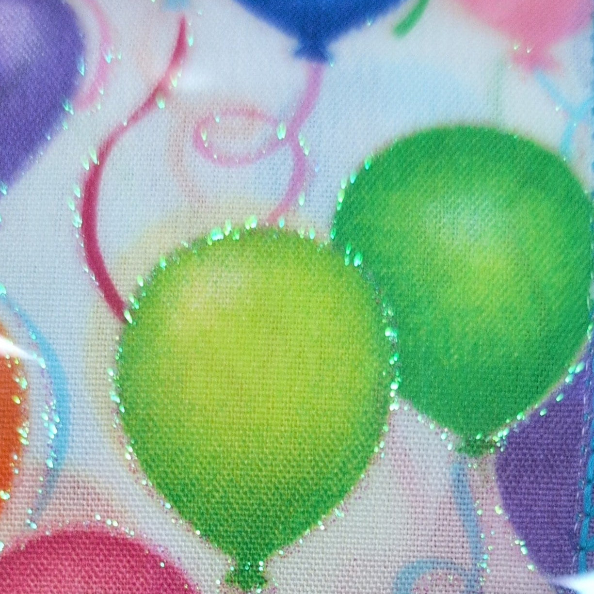 Spool of ribbon with colorful balloon design on a white background