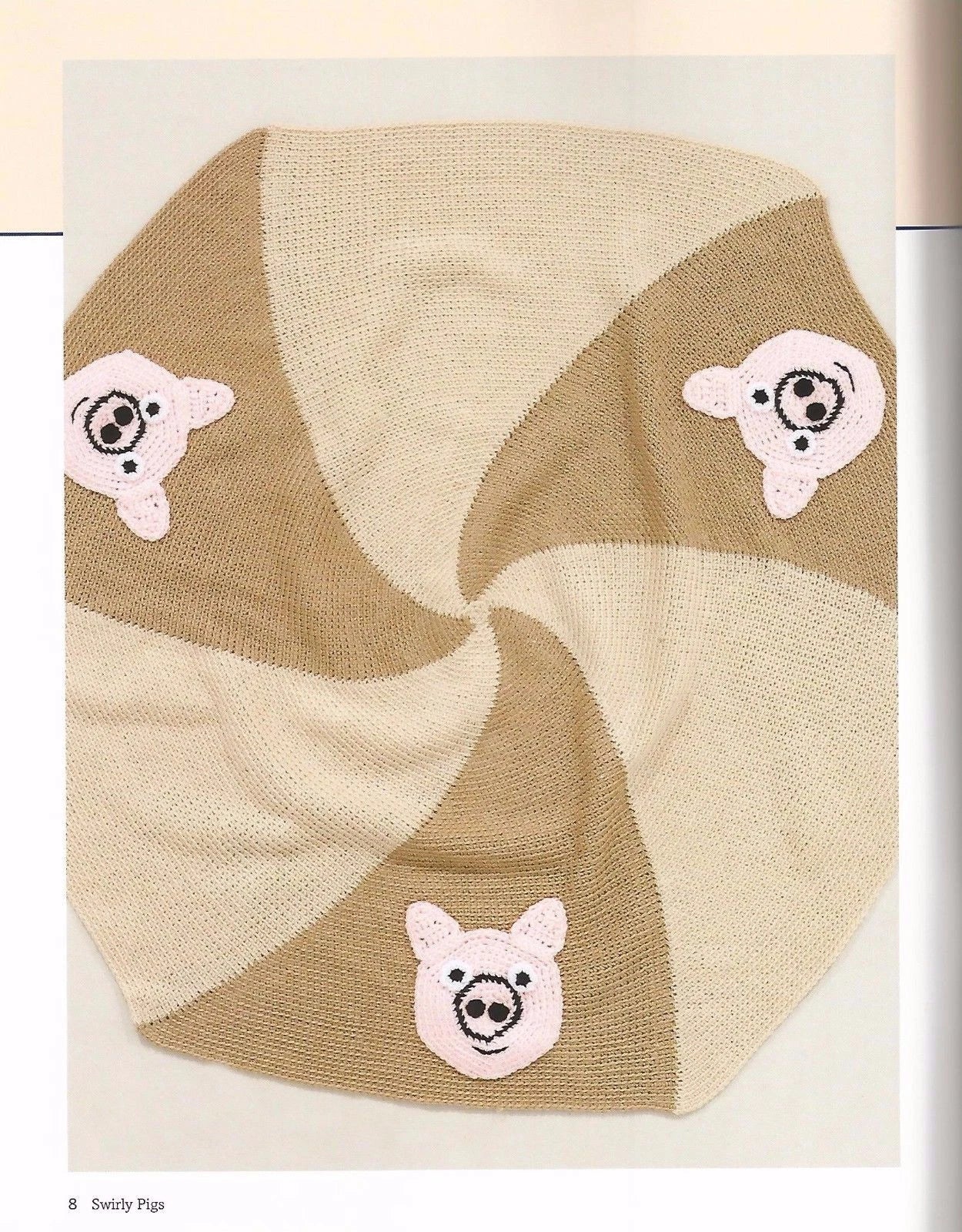 Knitted baby blanket with pig designs on a beige background