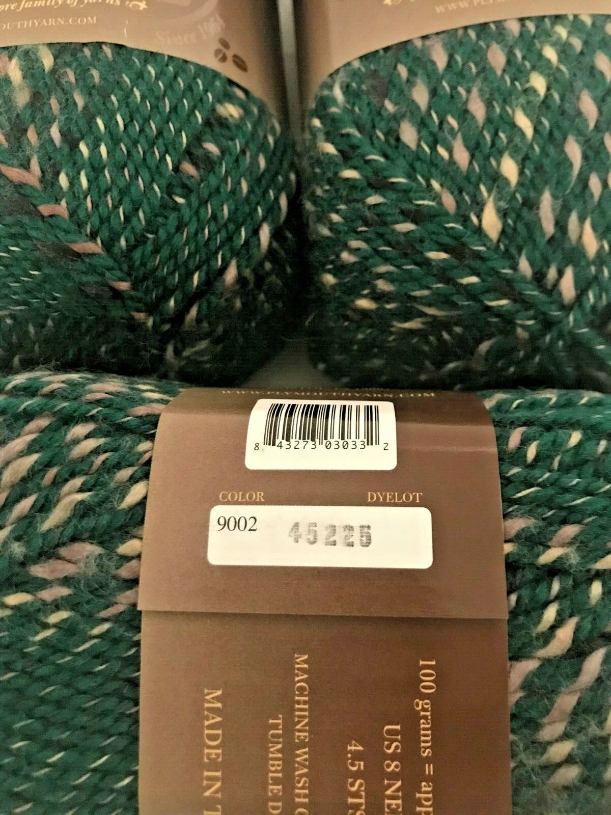 Three skeins of green yarn with labels on a white background