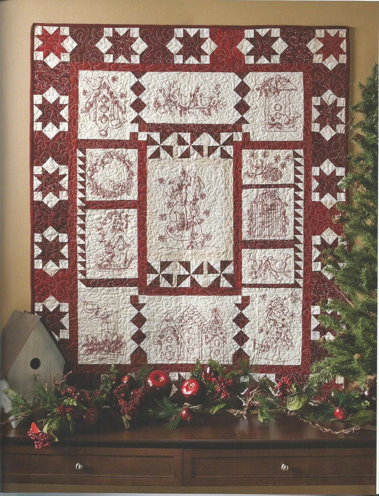 Quilt with red and white pattern displayed on a wall with Christmas decorations.