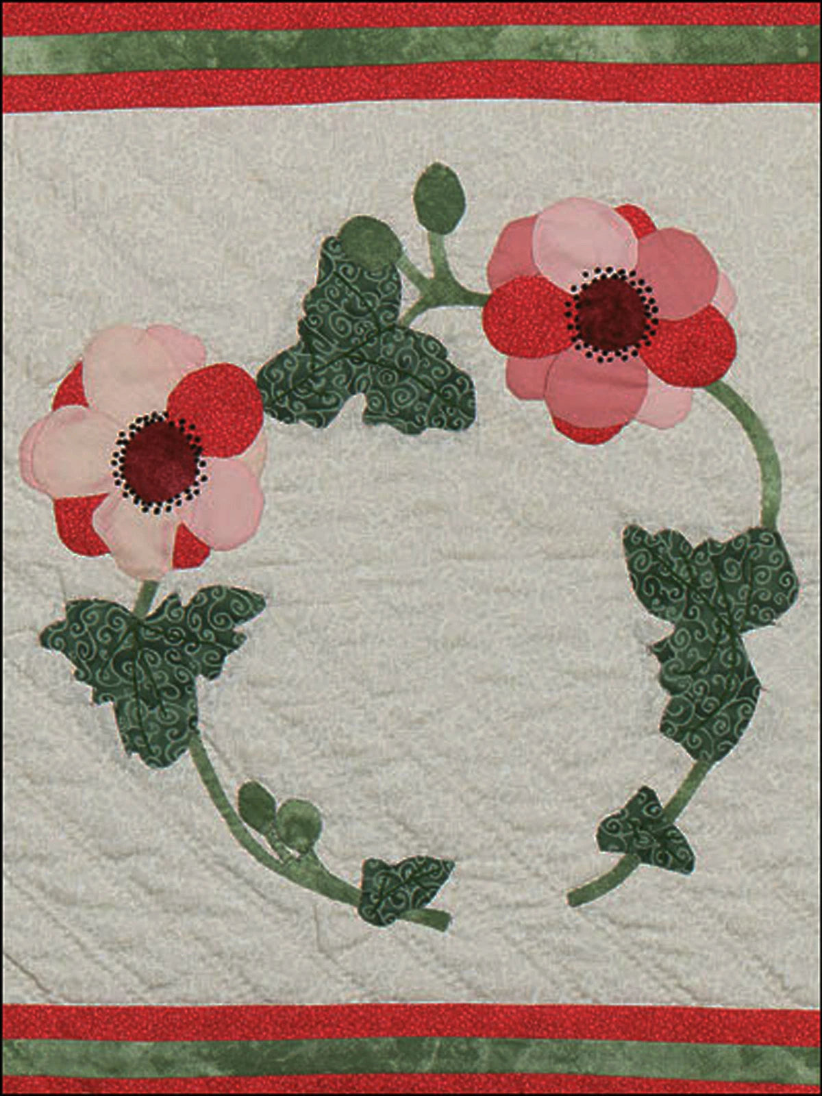 Quilt with floral design featuring pink flowers and green leaves on a white background.