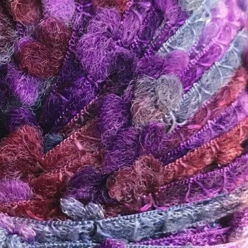 Multicolored yarn ball with purple, red, and gray tones on a white background