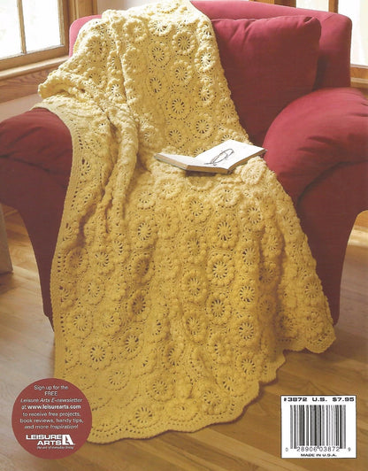 Yellow crocheted blanket draped over a red chair with a book on top, in a home setting.