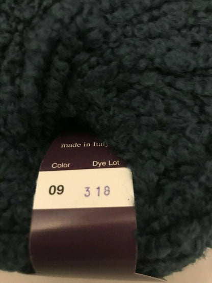 Close-up of a ball of dark yarn with a label showing 'made in Italy' and numbers.