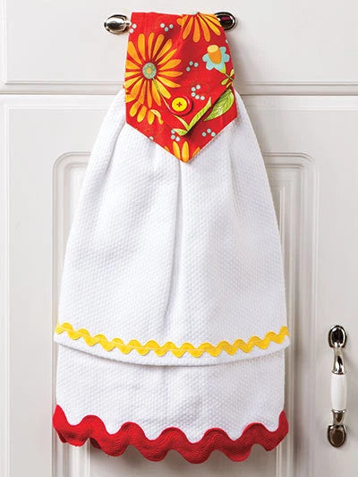 White towel with colorful floral design hanging on a white door