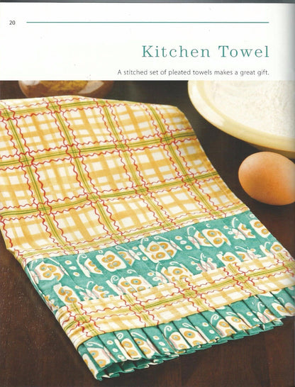 Colorful patterned kitchen towel on a wooden surface with text about it being a great gift.