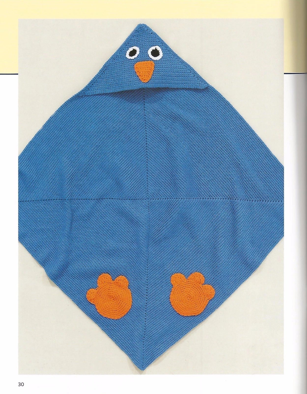 Blue knitted baby blanket with orange feet and eyes on a light background