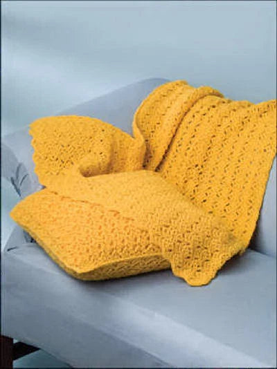 Yellow crocheted blanket draped over a gray sofa