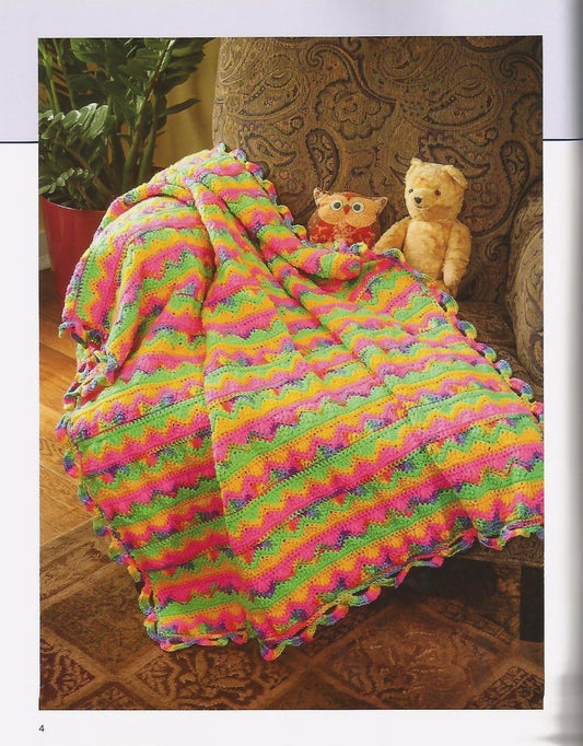 Colorful knitted blanket draped over a chair with two stuffed animals.