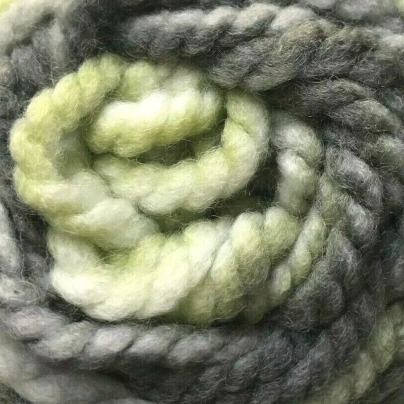 Coiled ball of green and gray yarn on a white background