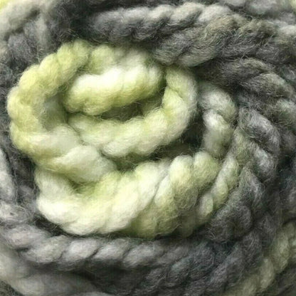Coiled ball of green and gray yarn on a white background