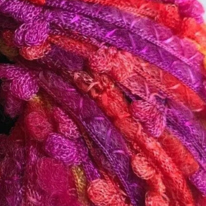Close-up of colorful yarn skeins in shades of pink, purple, and red.