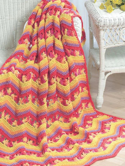 Colorful crocheted blanket draped over a chair with a white background