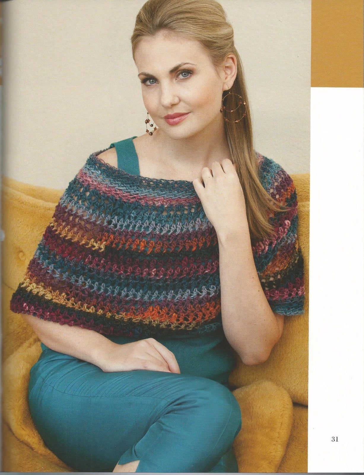 Woman wearing a colorful crocheted shrug sitting on a yellow couch.