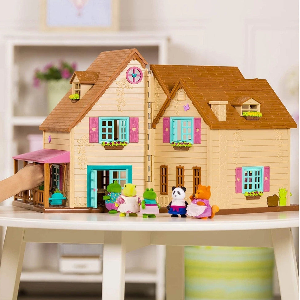 Child playing with a wooden dollhouse and accessories on a table.