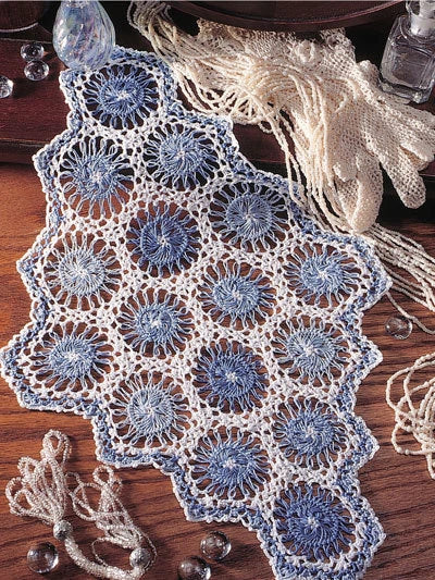 Crocheted doily with blue and white pattern on a wooden surface