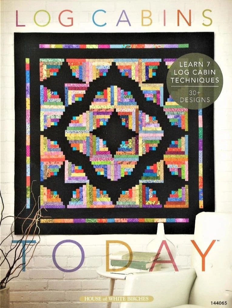 Quilt with log cabin pattern on a white wall, featuring text about log cabin techniques and designs.