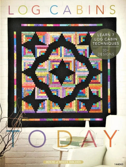 Quilt with log cabin pattern on a white wall, featuring text about log cabin techniques and designs.