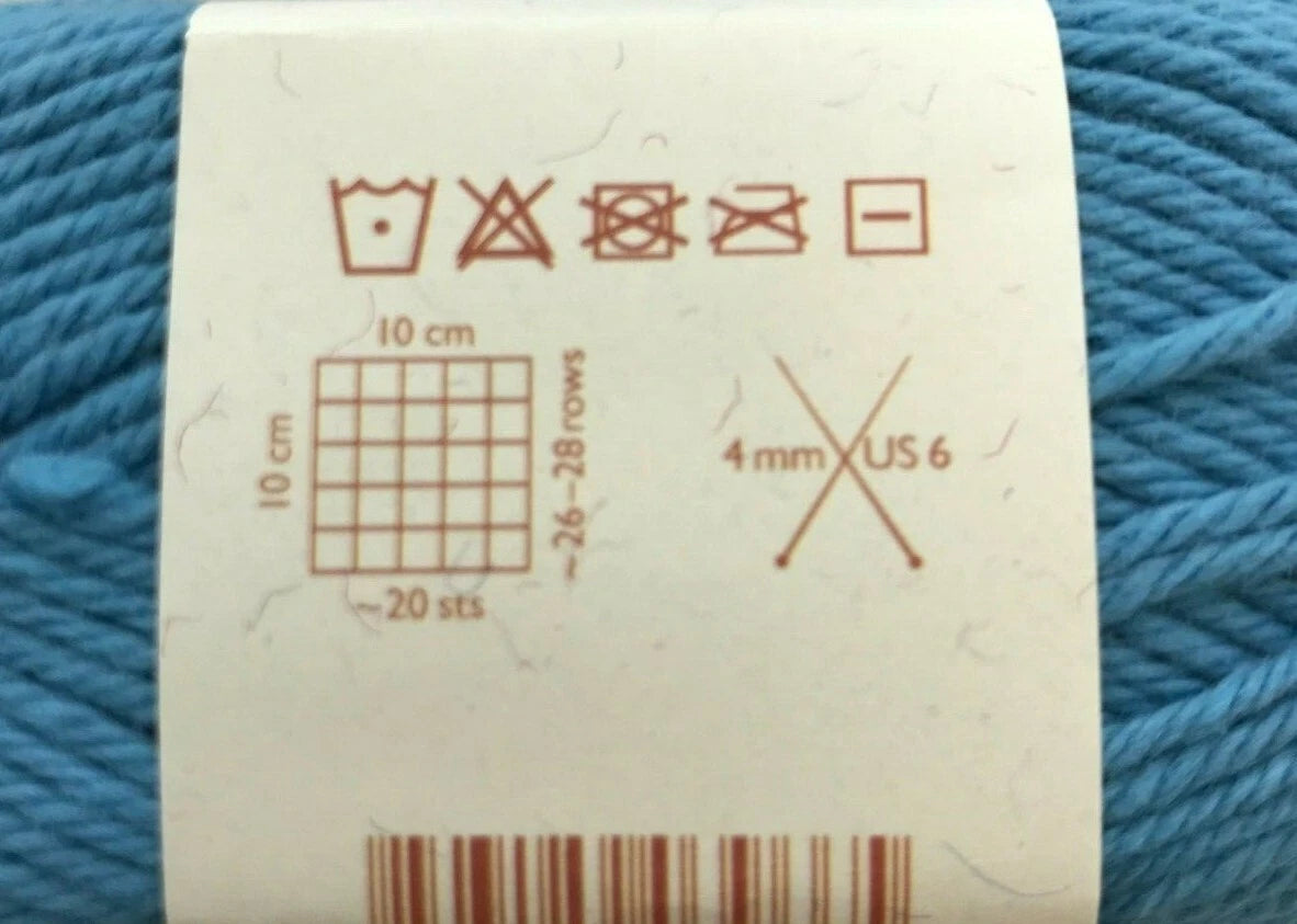 Yarn label with measurement and care instructions on a blue yarn background