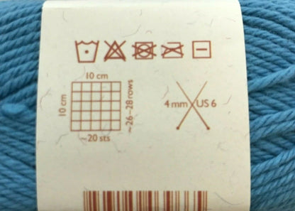 Yarn label with measurement and care instructions on a blue yarn background