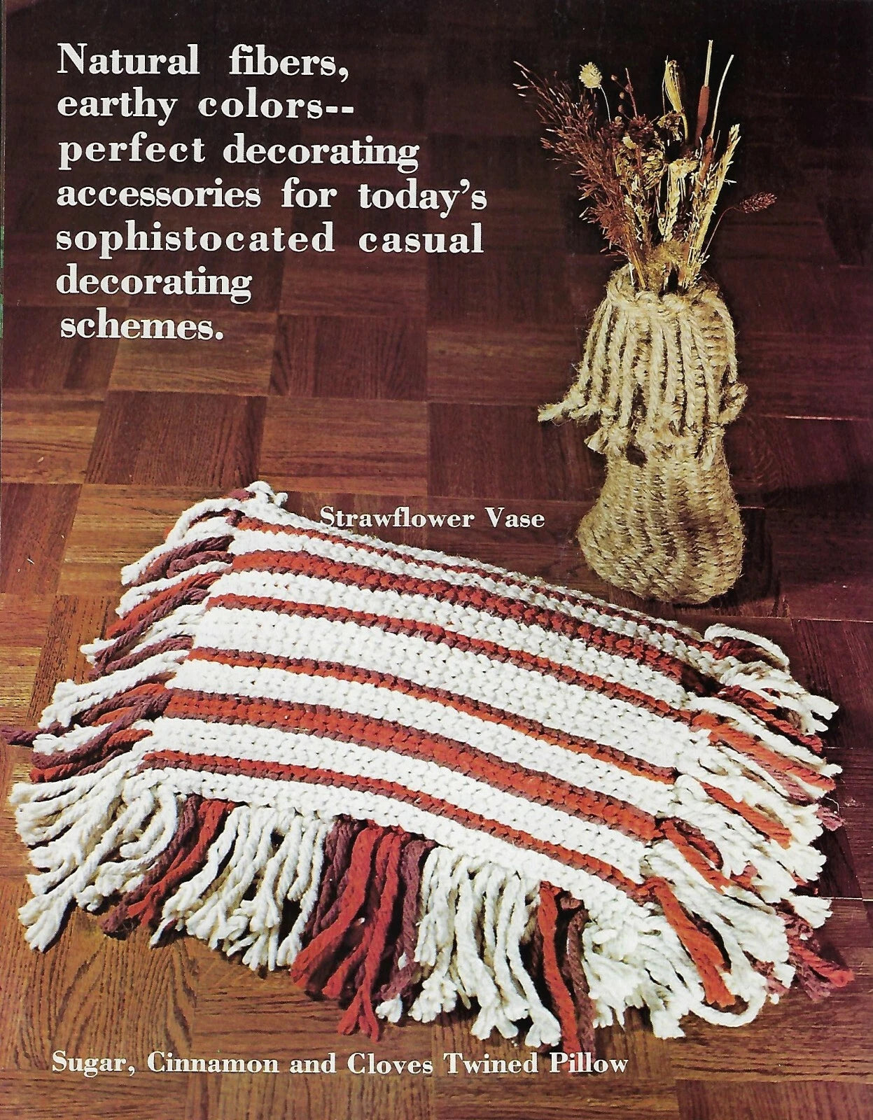 Decorative pillow with fringes and a strawflower vase on a wooden floor.