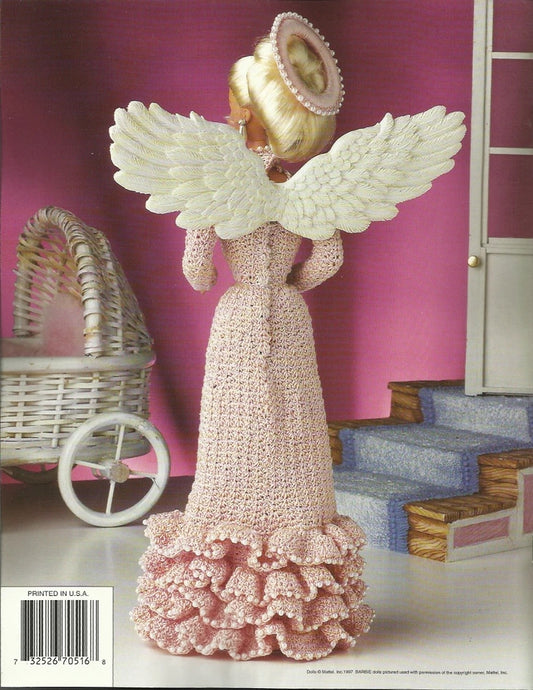 Knitted angel figurine with pink dress and white wings in a dollhouse setting.