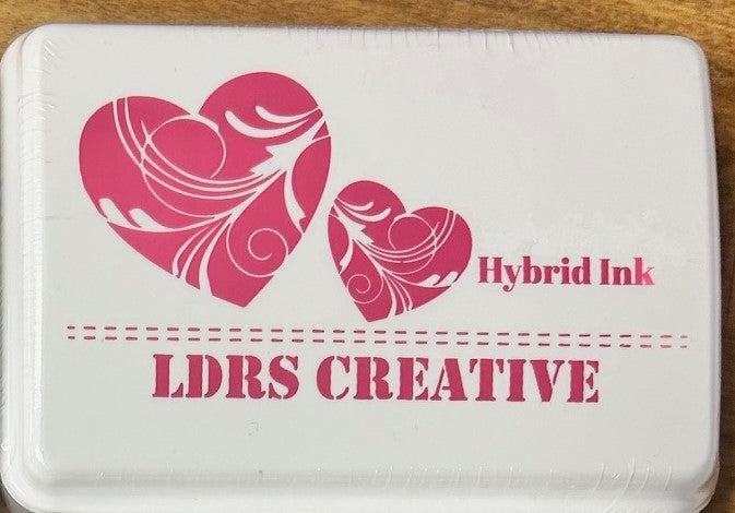 An image of a white ink pad featuring two pink hearts and the text "LDRS CREATIVE Hybrid Ink" in a bright pink/magenta color.