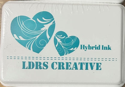 An image of a white ink pad featuring two teal-colored hearts with white decorative swirls and the text "LDRS CREATIVE Hybrid Ink" in teal.