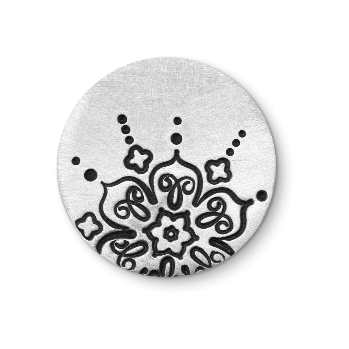 Circular metal stamp with floral design on a white background